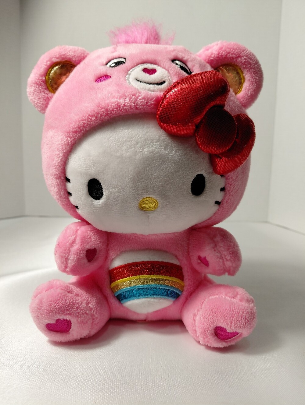 Hello Kitty Dressed In Pink Care Bear Costume with Red Bow & Rainbow Belly Plush